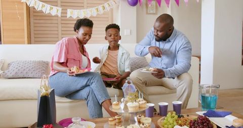 African American Family Celebrating Birthday at Home Sharing Cupcakes on Couch Together