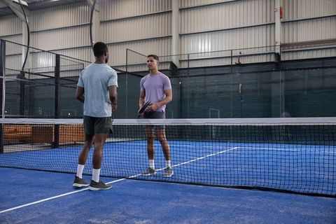 Multiethnic men meeting on indoor padel court preparing for friendly match