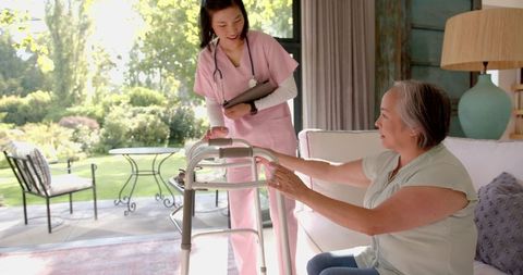 Caregiver assisting senior woman with walker in home setting