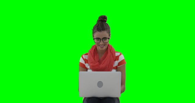 Woman smiling while using a laptop with a vibrant green background. Ideal for tech advertisements, e-learning platforms, or website design templates requiring a person engaging with technology.