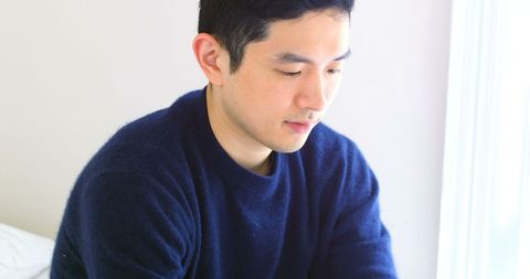 Asian Man in Casual Attire Contemplating in Bright Room