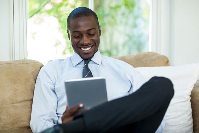 Young man sitting on sofa and using digital tablet at home