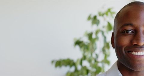 Smiling Professional Man in Office Setting with Plant Background