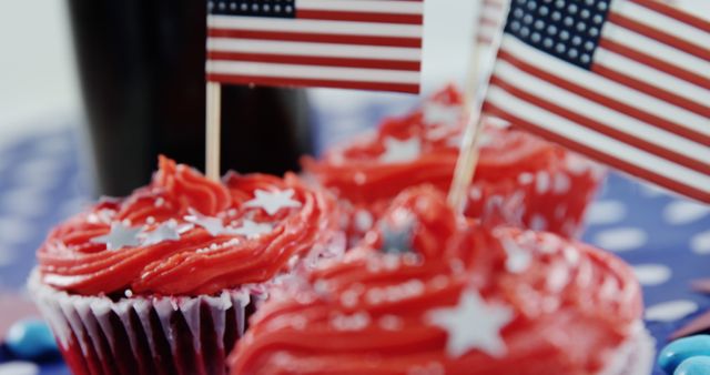 Red frosted cupcakes adorned with American flags suggest a patriotic celebration, with copy space. These treats are often seen at events like Independence Day parties or Memorial Day gatherings.