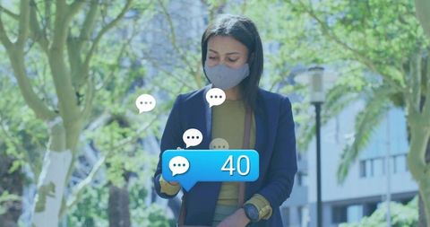 Professional woman wearing mask checking phone with 40 message alert in urban park spring