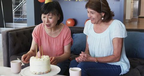 Senior friends celebrating birthday with cake and coffee in cozy living room