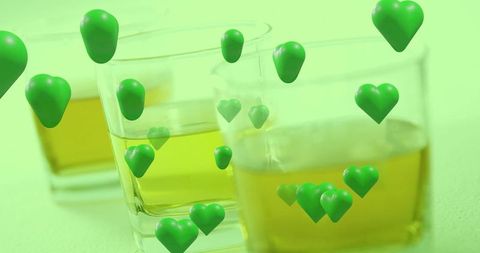Floating green hearts over glass tumblers with golden liquid mint mood abstract wellness