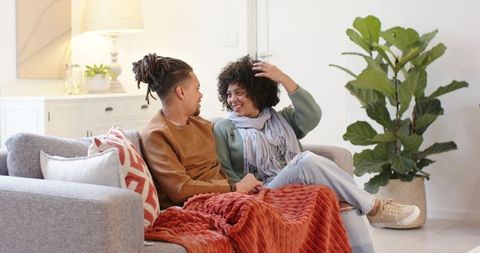 African American couple sharing cozy moment on modern grey sofa with rust blanket