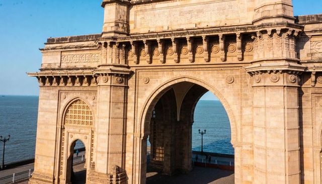 Golden gateway arch on mumbai seafront promenade with ornate stonework and sea view
