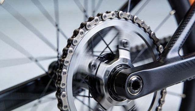 Spinning bicycle drivetrain macro detail showing chainring, chain, crank and hub