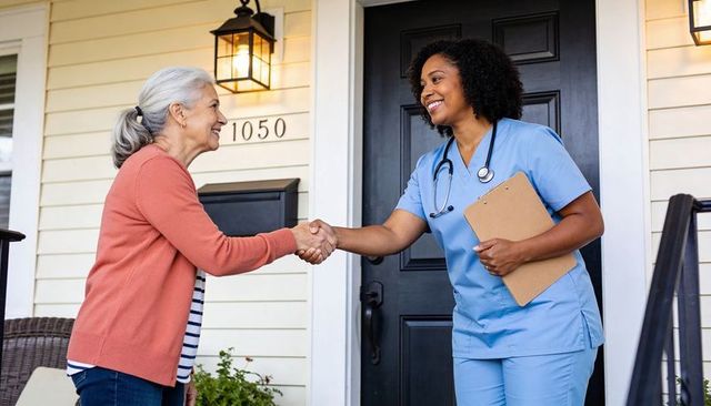 Home nurse greeting senior on front porch shaking hands caregiver arriving for visit