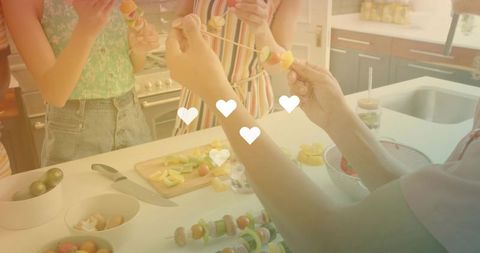 Friends assembling colorful fruit and vegetable skewers on sunlit kitchen counter