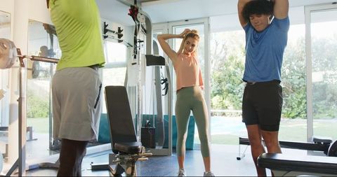 Diverse Group Stretching in Modern Gym with Trainer Guidance
