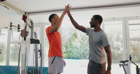 Two Fit Men Celebrating Achievements in Home Gym Setting