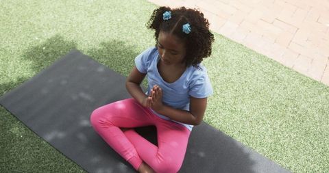 Young Girl Meditating Outdoors on Yoga Mat in School Yard
