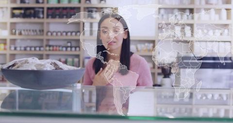 Standing retail clerk behind glass counter with world map overlay representing global trade