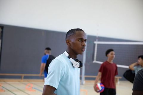 High school volleyball training showing focused athlete wearing headphones and teammates