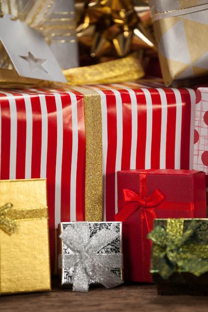This image showcases a close-up view of various beautifully wrapped gift boxes on a wooden table, perfect for Christmas and holiday-themed projects. The vibrant colors and festive wrapping make it ideal for use in holiday advertisements, greeting cards, social media posts, and seasonal promotions.