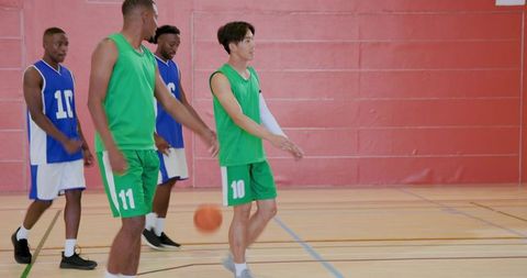 Basketball player pointing and directing teammates during indoor scrimmage with ball in play