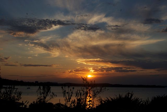 Dramatic Sunset Over Calm Lake with Silhouetted Foliage - Download Free Stock Photos Pikwizard.com