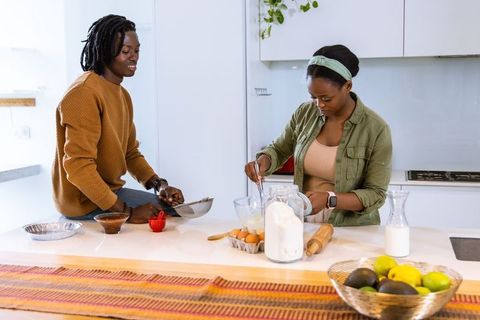 African american couple preparing batter and baking together in bright modern kitchen