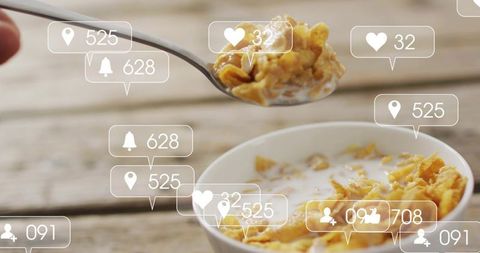 Lifting spoonful of milky cornflakes above white bowl with social media icons overlay