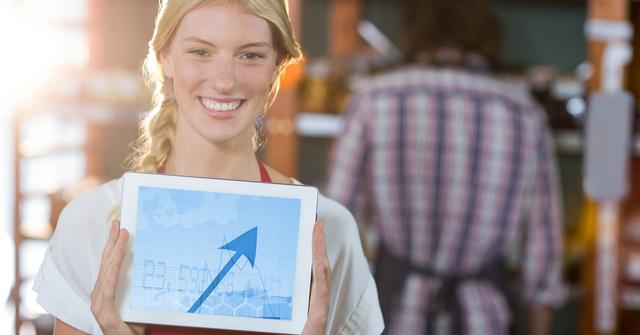 Portrait of a happy woman holding digital tablet displaying arrow sign
