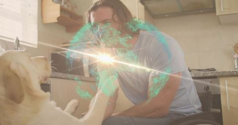 Wheelchair user sharing moment with dog holding paw beside digital globe in sunny kitchen