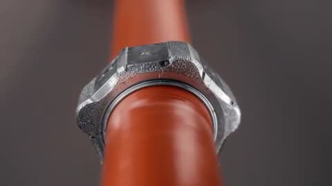 Macro video of red conduit sliding through hex nut revealing washer, industrial closeup