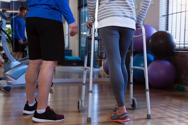 Physiotherapist assisting patient with walking frame in clinic. Ideal for illustrating physical therapy, rehabilitation, and healthcare support. Useful for medical articles, physiotherapy services, and fitness training programs.