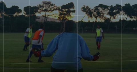 Female Goalkeeper Observing Team on Outdoor Field at Dusk