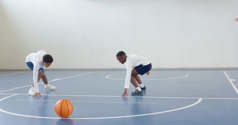 Youth practice basketball defense skills on indoor court