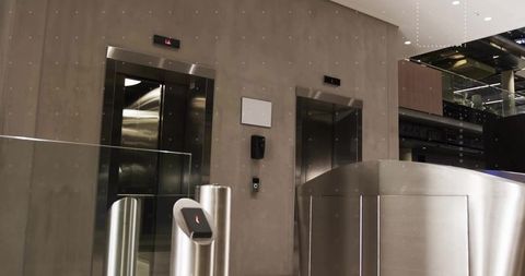Modern corporate lobby with security turnstile and elevator doors