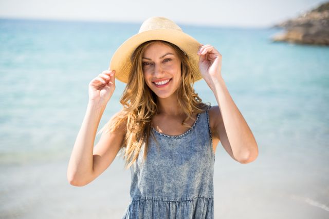 Portrait of smiling young woman standing against sea on sunny day