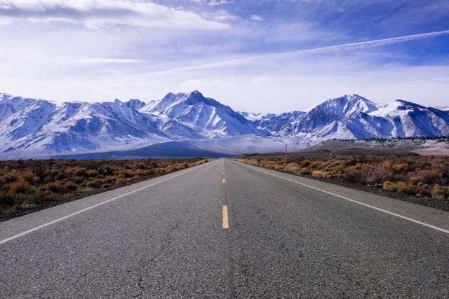 Empty Road Leading Towards Snowcapped Mountains Under Clear Blue Sky - Download Free Stock Photos Pikwizard.com