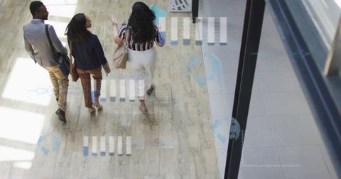 Walking Business Team Collaborating in Sunlit Office Corridor