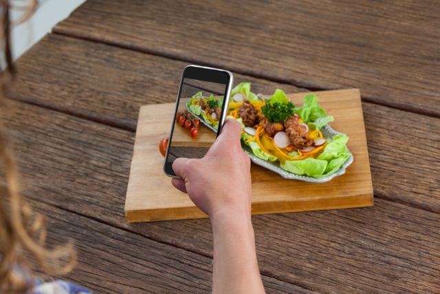 Close-up of photographer clicking a picture of food using smartphone