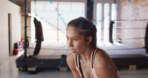 Female athlete pushing through fatigue during boxing training with biometric overlay