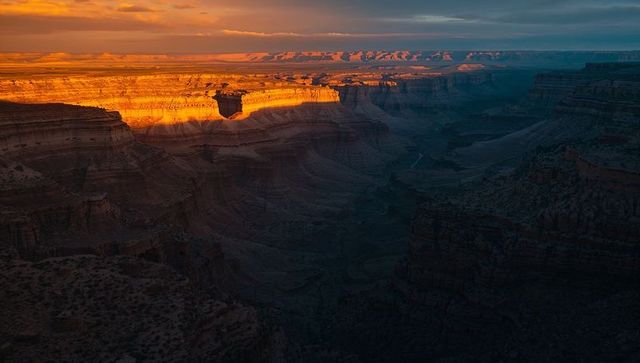 Sunlit canyon rim casting golden glow across deep desert gorge at sunset
