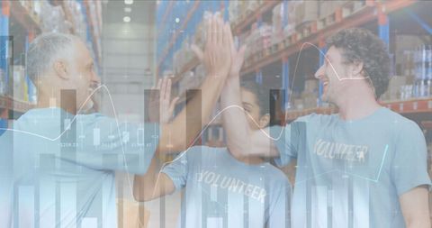 Diverse Volunteers Celebrating Teamwork in Warehouse with Financial Overlay