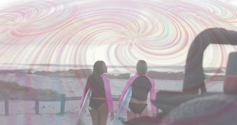 Surfers strolling on beach paradise at dusk