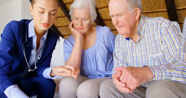 Nurse communicating with elderly couple in domestic environment, providing medical consultation or advice. Image best used for healthcare advertising, elder care services, medical advice articles, or home healthcare marketing materials.