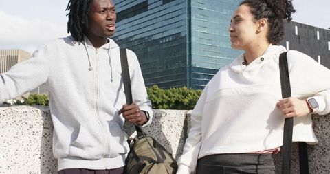 Commuters Chatting on Urban Overpass with Backpacks by Modern Glass Office Tower
