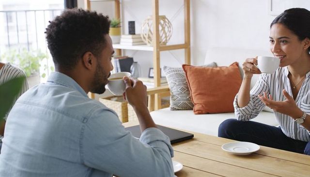 Casual coworking conversation over coffee in modern living room with laptop and cozy decor