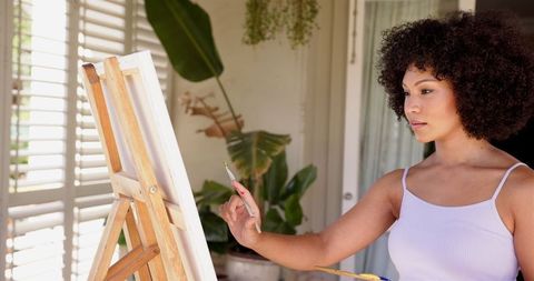 Artist painting on canvas in bright studio setting