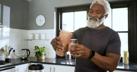 Senior man enjoying morning smoothie in modern kitchen
