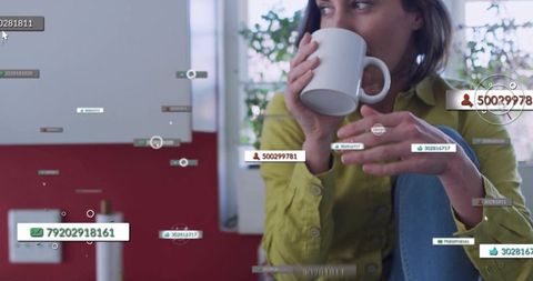 Woman sipping coffee holding mug with digital data overlays in sunlit home interior