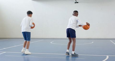 Active Young Athletes Dribbling Basketballs in Gym
