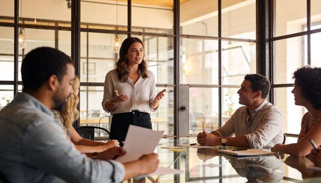 Business Leader Presenting Strategy in Modern Glass Conference Room with Collaborative Team