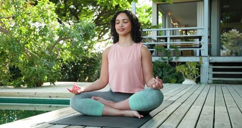 Tranquil meditation by pool on sunny deck